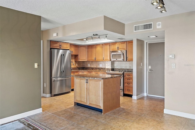 kitchen featuring appliances with stainless steel finishes, a textured ceiling, a center island, and light tile patterned floors