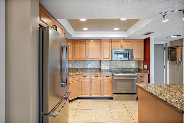 kitchen featuring appliances with stainless steel finishes, light stone countertops, and a tray ceiling