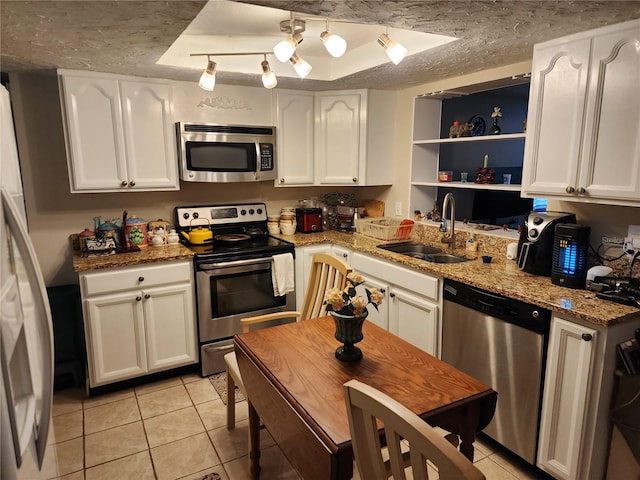 kitchen with sink, light stone countertops, light tile patterned flooring, white cabinetry, and appliances with stainless steel finishes