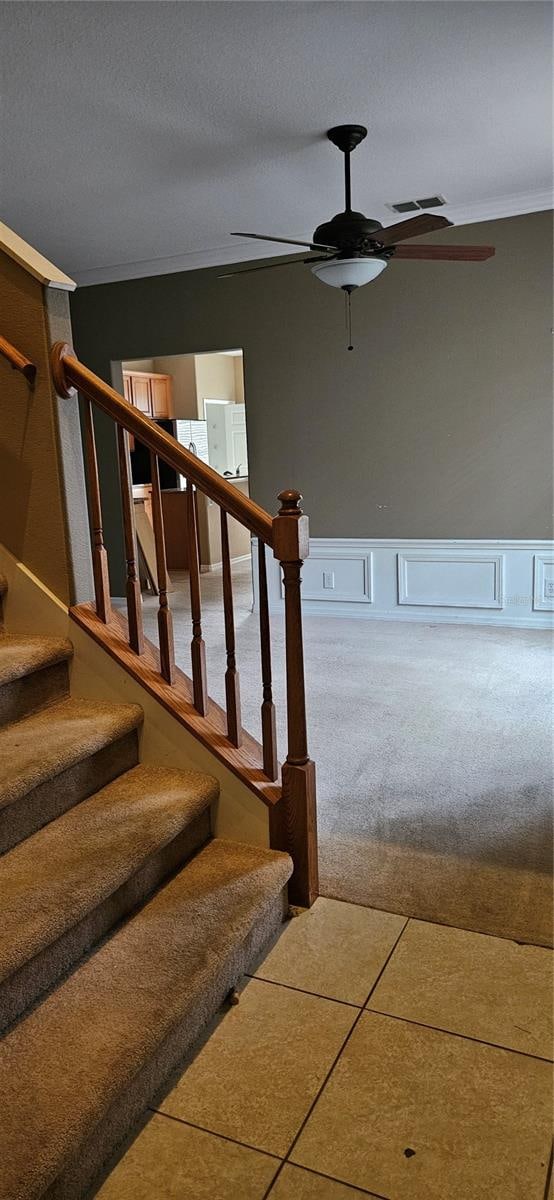 stairs with crown molding, a textured ceiling, tile patterned flooring, and ceiling fan