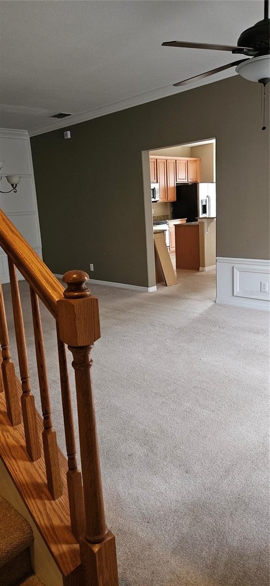 stairs with crown molding, carpet, and ceiling fan