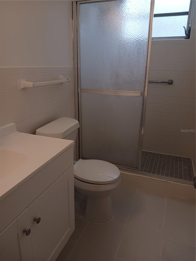 bathroom featuring an enclosed shower, toilet, tile walls, vanity, and tile patterned flooring