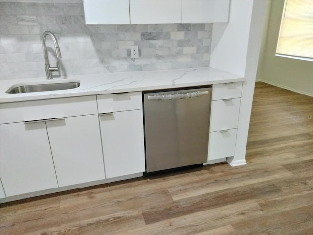 kitchen featuring white cabinets, light wood-type flooring, dishwasher, sink, and light stone counters