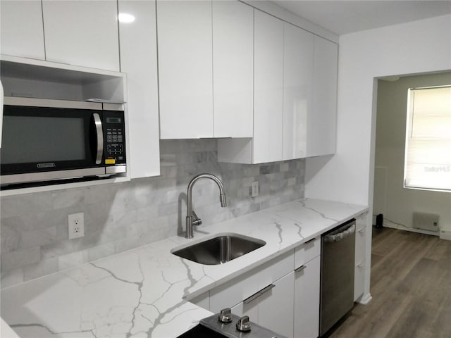 kitchen featuring white cabinets, dark hardwood / wood-style flooring, appliances with stainless steel finishes, light stone countertops, and sink