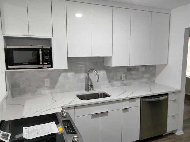 kitchen with dark wood-type flooring, sink, light stone countertops, white cabinetry, and appliances with stainless steel finishes