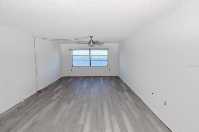 empty room featuring ceiling fan, a textured ceiling, and light hardwood / wood-style flooring