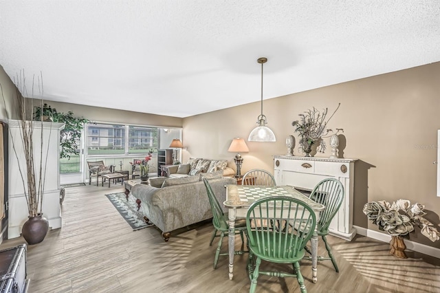 dining space with light hardwood / wood-style floors and a textured ceiling