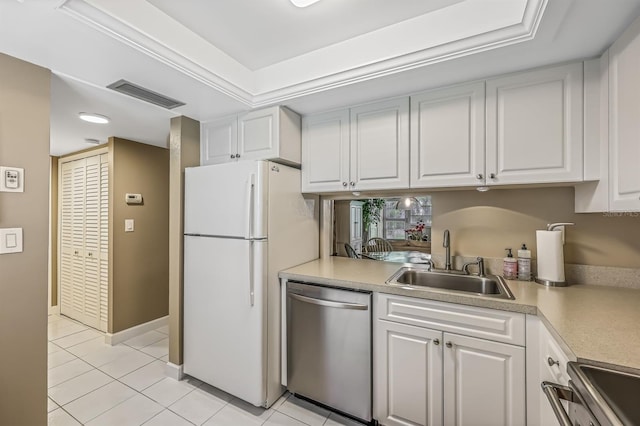 kitchen with a tray ceiling, sink, white cabinets, light tile patterned flooring, and appliances with stainless steel finishes