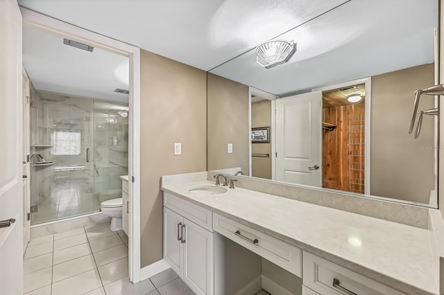 bathroom with vanity, toilet, tile patterned floors, and a shower with shower door