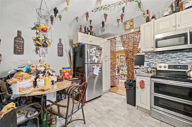 kitchen featuring a textured ceiling, light hardwood / wood-style flooring, stainless steel appliances, and white cabinets