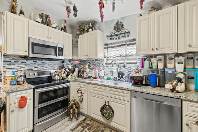 kitchen with decorative backsplash, sink, appliances with stainless steel finishes, and light stone counters