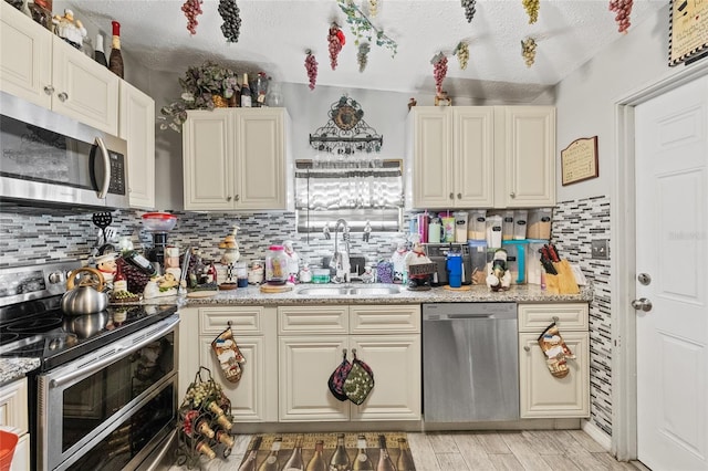 kitchen with light hardwood / wood-style flooring, a textured ceiling, stainless steel appliances, and sink