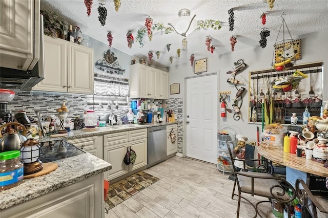 kitchen featuring appliances with stainless steel finishes, light stone counters, a textured ceiling, and backsplash