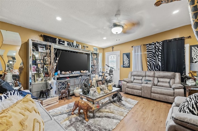 living room with ceiling fan, a textured ceiling, and light hardwood / wood-style flooring