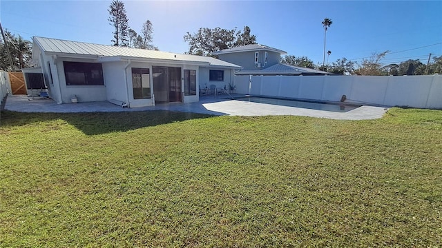 rear view of property with a yard, a swimming pool, and a patio area