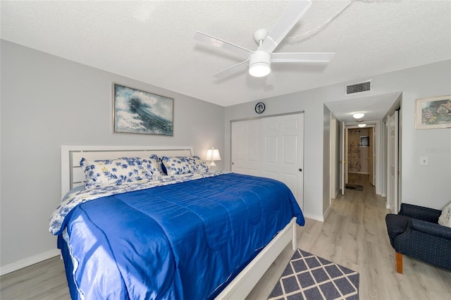 bedroom featuring hardwood / wood-style floors, a textured ceiling, a closet, and ceiling fan