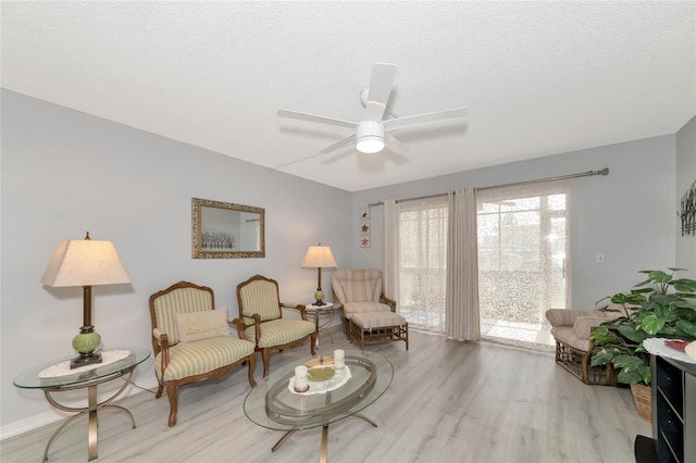 living area with a textured ceiling, light hardwood / wood-style floors, and ceiling fan