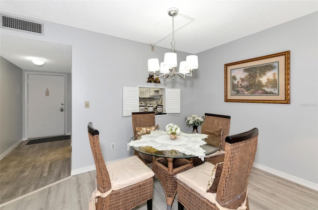 dining area featuring hardwood / wood-style flooring and an inviting chandelier