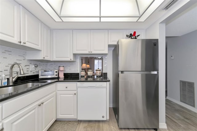 kitchen with stainless steel refrigerator, dishwasher, white cabinets, and light hardwood / wood-style flooring