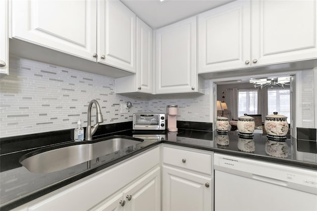 kitchen with white cabinetry, sink, white dishwasher, a chandelier, and decorative backsplash