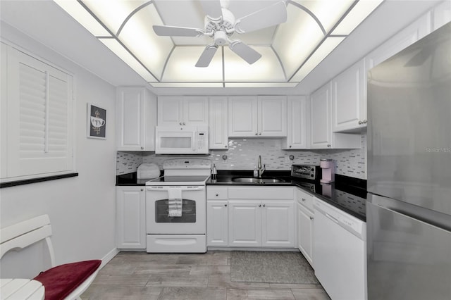 kitchen with backsplash, white appliances, ceiling fan, sink, and white cabinets