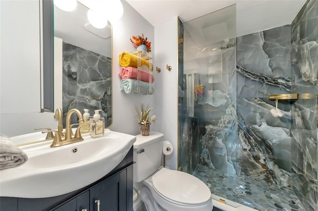 bathroom with a tile shower, vanity, and toilet