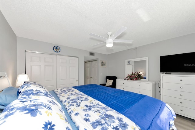 bedroom with ceiling fan, hardwood / wood-style floors, and a textured ceiling