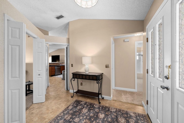 hall with lofted ceiling, a textured ceiling, and light tile patterned floors