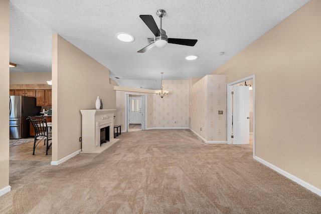 unfurnished living room featuring ceiling fan with notable chandelier, a textured ceiling, and light carpet