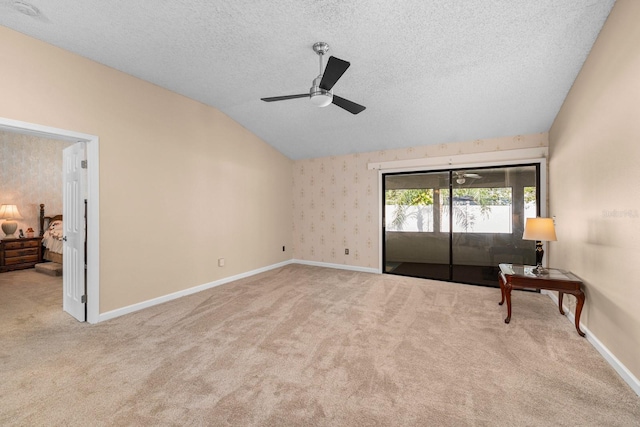 interior space with ceiling fan, vaulted ceiling, light carpet, and a textured ceiling