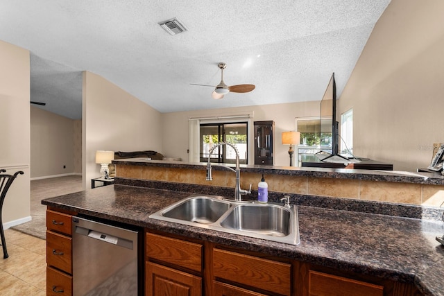 kitchen with ceiling fan, a textured ceiling, sink, stainless steel dishwasher, and lofted ceiling