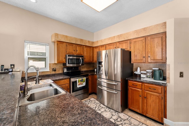 kitchen featuring a textured ceiling, light tile patterned floors, decorative backsplash, appliances with stainless steel finishes, and sink