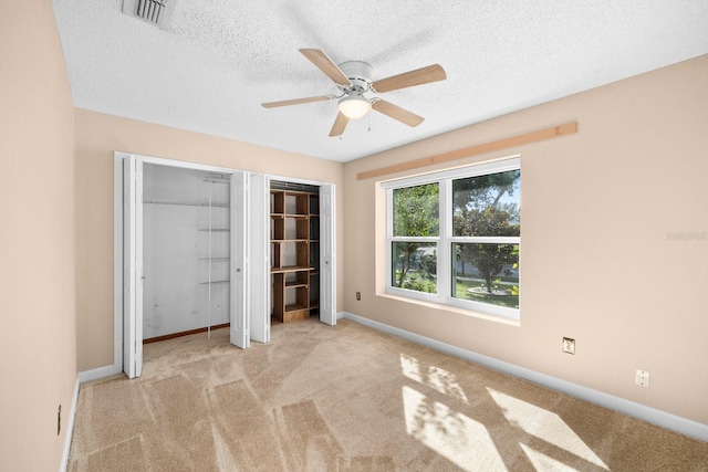 unfurnished bedroom with a textured ceiling, ceiling fan, and light colored carpet