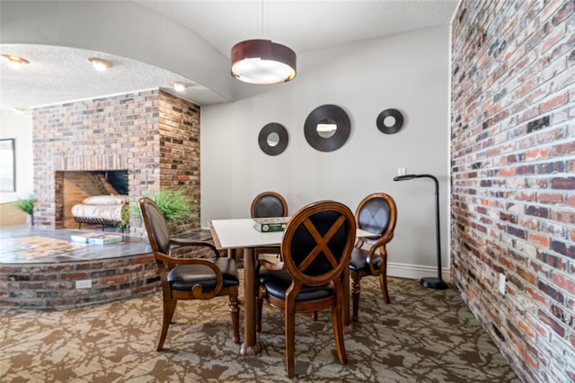 dining area with brick wall and a brick fireplace