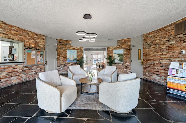 living room with a notable chandelier, brick wall, and a textured ceiling