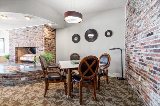 5200 Brittany Dr S Unit 1202, Saint Petersburg, FL 33715 - dining area featuring brick wall, carpet, a textured ceiling, and a brick fireplace