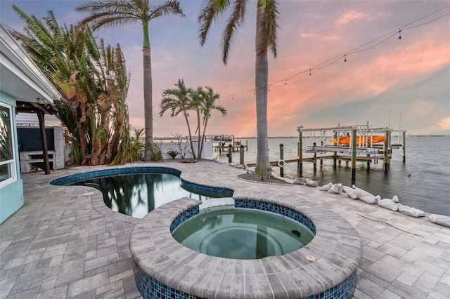 pool at dusk with a patio, a boat dock, an in ground hot tub, and a water view