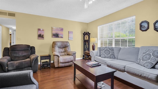 living room featuring dark wood-type flooring, a textured ceiling, and ceiling fan