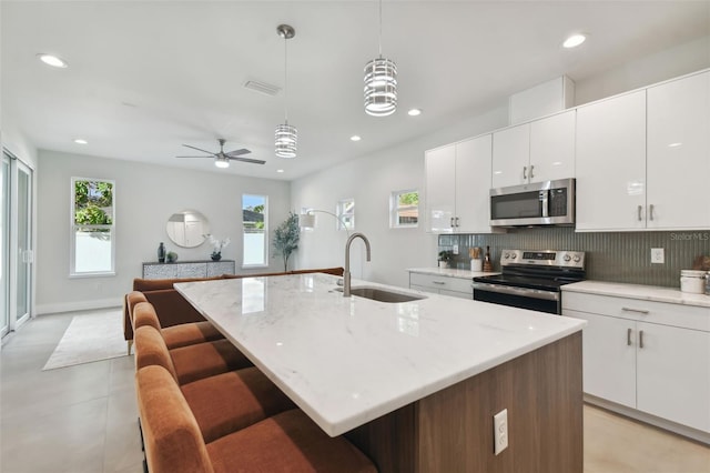 kitchen with sink, appliances with stainless steel finishes, and a kitchen island with sink