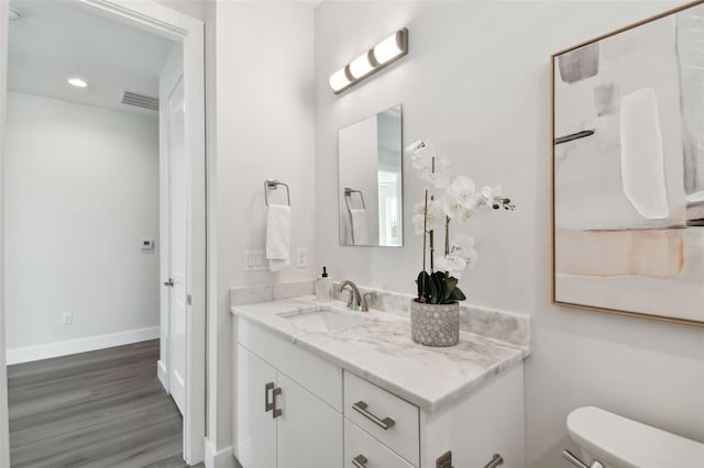 bathroom with vanity, toilet, and hardwood / wood-style floors