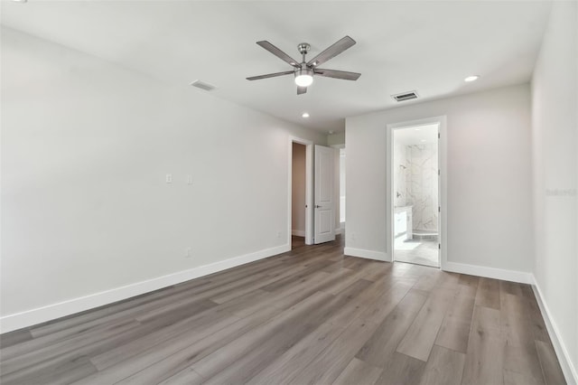 unfurnished bedroom with ensuite bathroom, light wood-type flooring, and ceiling fan