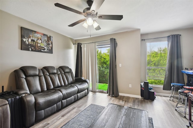 living room with baseboards, wood finished floors, and a ceiling fan