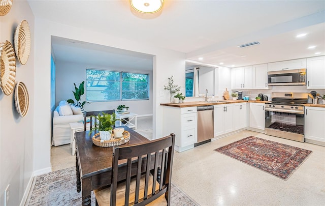 kitchen featuring sink, appliances with stainless steel finishes, white cabinetry, and wood counters