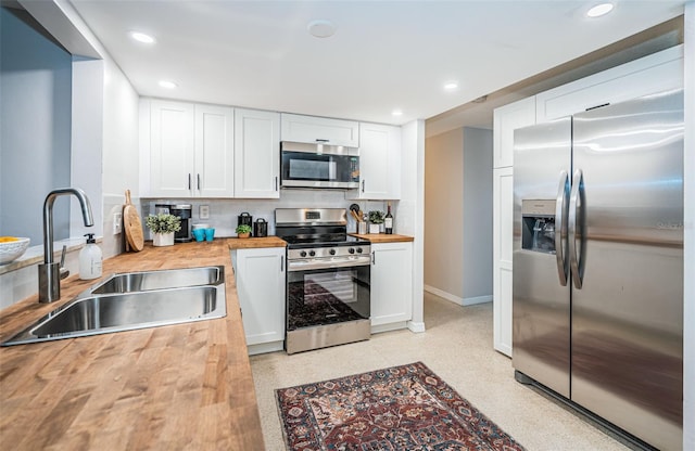 kitchen with wood counters, sink, stainless steel appliances, and white cabinets