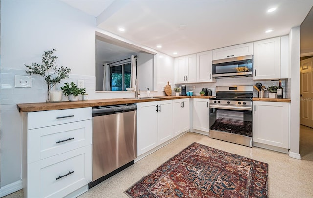 kitchen with sink, appliances with stainless steel finishes, white cabinets, and butcher block counters