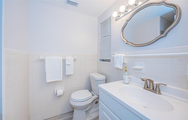 bathroom featuring vanity, toilet, and tile walls