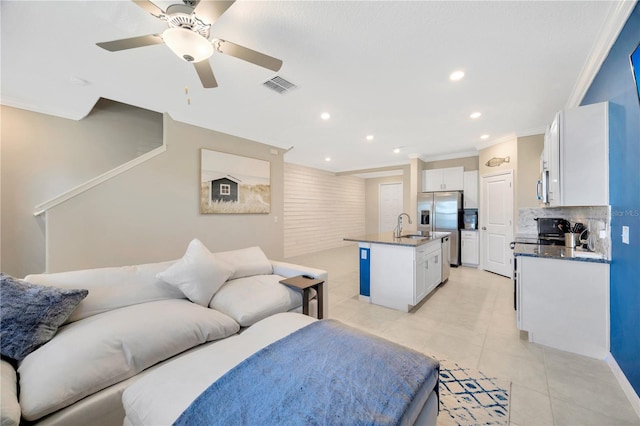 interior space with appliances with stainless steel finishes, white cabinets, a kitchen island with sink, and ornamental molding