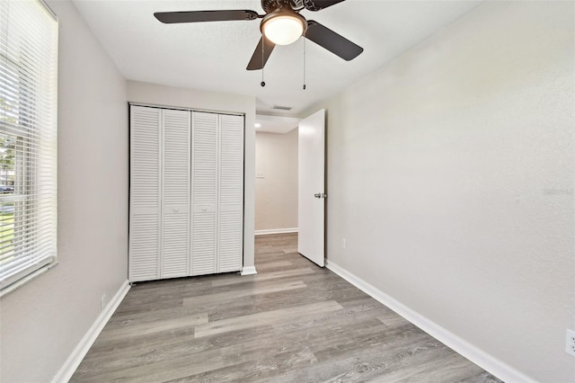 unfurnished bedroom with light wood-type flooring, a closet, and ceiling fan