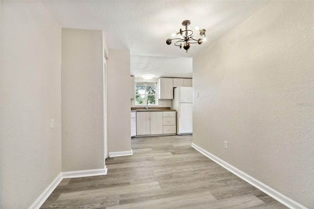 hallway with light hardwood / wood-style flooring and a chandelier