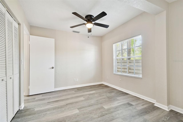 unfurnished bedroom featuring a closet, light hardwood / wood-style floors, and ceiling fan